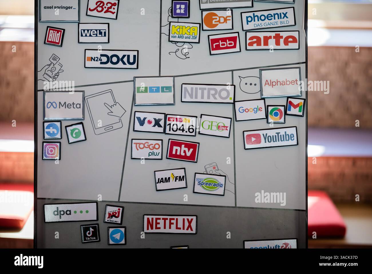 Berlin, Deutschland. April 2025. Logos verschiedener Medien- und Digitalunternehmen – darunter öffentliche Rundfunkanstalten, private Rundfunkanstalten, Social-Media-Plattformen und Streaming-Dienste – auf einer Magnettafel während sie in der America Memorial Library am DesInfoPoint für Medienkompetenz und den Umgang mit Fake News waren. Das Motto der vom Deutschen Bibliotheksverband (dbv) organisierten "Nacht der Bibliotheken" lautet "Wissen". Teilen. Entdecken“. Quelle: Christoph Soeder/dpa/Alamy Live News Stockfoto