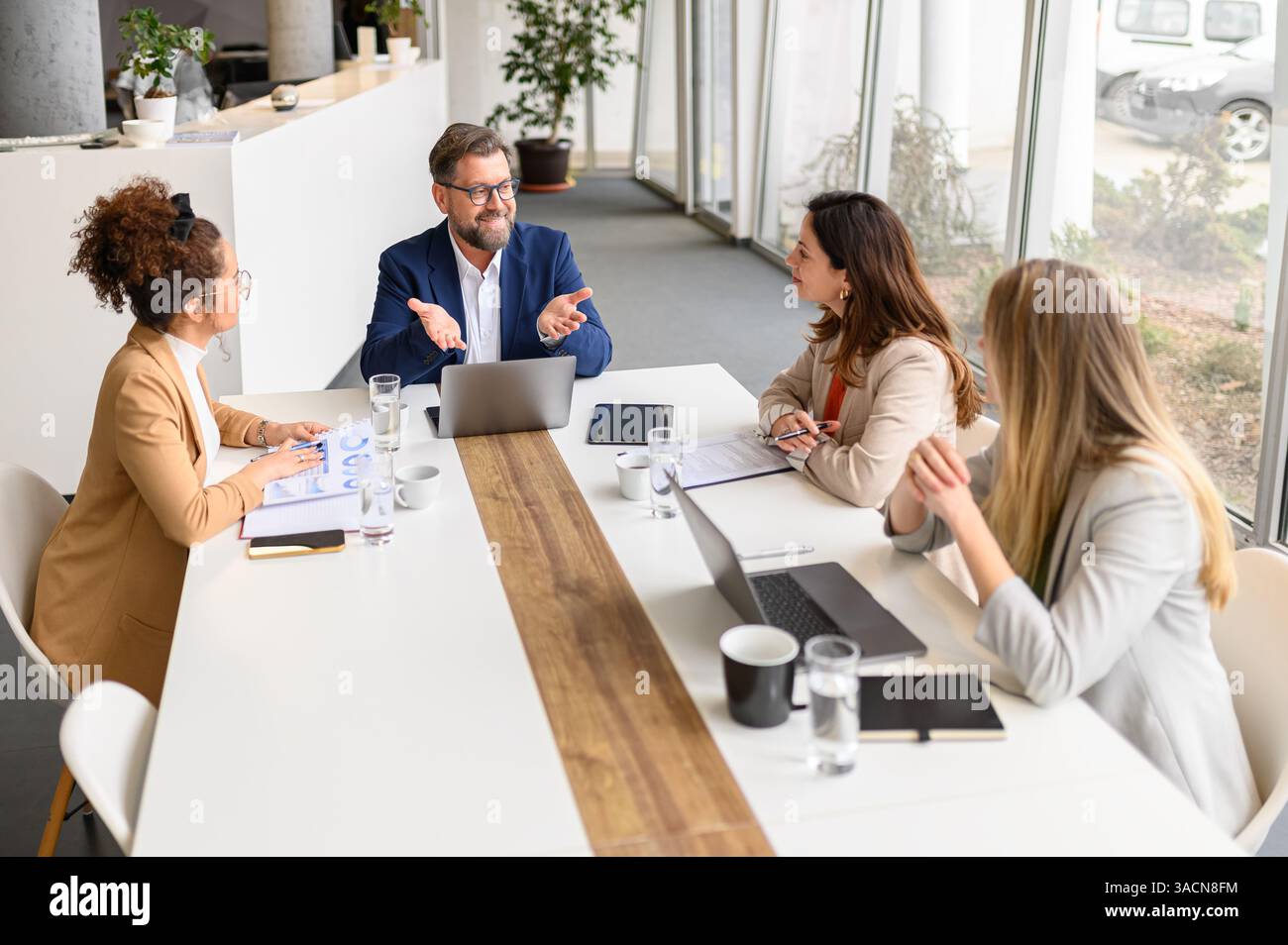 Hochwinkelansicht eines männlichen Anwalts mit Gesten auf dem Laptop und Erläuterung von Projektdetails für weibliche Kollegen im Meeting Stockfoto