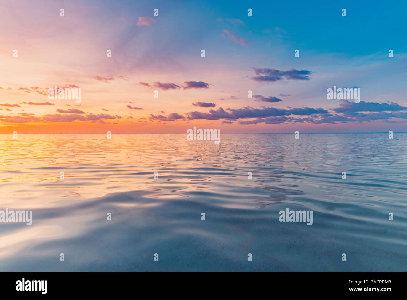 Farbenfrohe Wolken, sanfte Wellen, die eine entspannende Wasseroberfläche und Reflexionen inspirieren. Meditationstapete Stockfoto