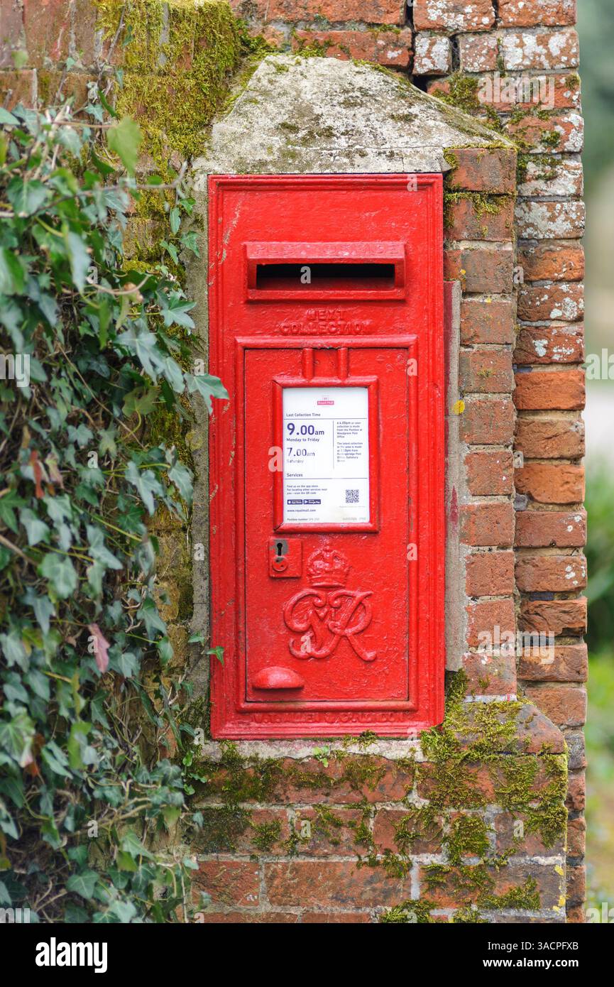 Roter Briefkasten von Royal Mail in einer Backsteinmauer in ländlicher Umgebung Stockfoto