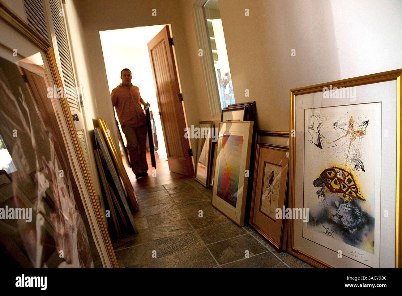 Angelo Benjamin Amadio trägt am Mittwoch, den 30. September 2009, ein Paar Gemälde durch einen Flur in seinem Haus in Pebble Beach, Kalifornien. 13 Kunstwerke im Wert von 7 Millionen wurden dem Anwesen bei einem Einbruch am Freitag entnommen. Ganz rechts ist ein Schildkrötenbild von Salvador Dali. Foto von David Royal für The Monterey County Herald (Kreditbild: Monterey Herald/ZUMAPRESS.com) Stockfoto