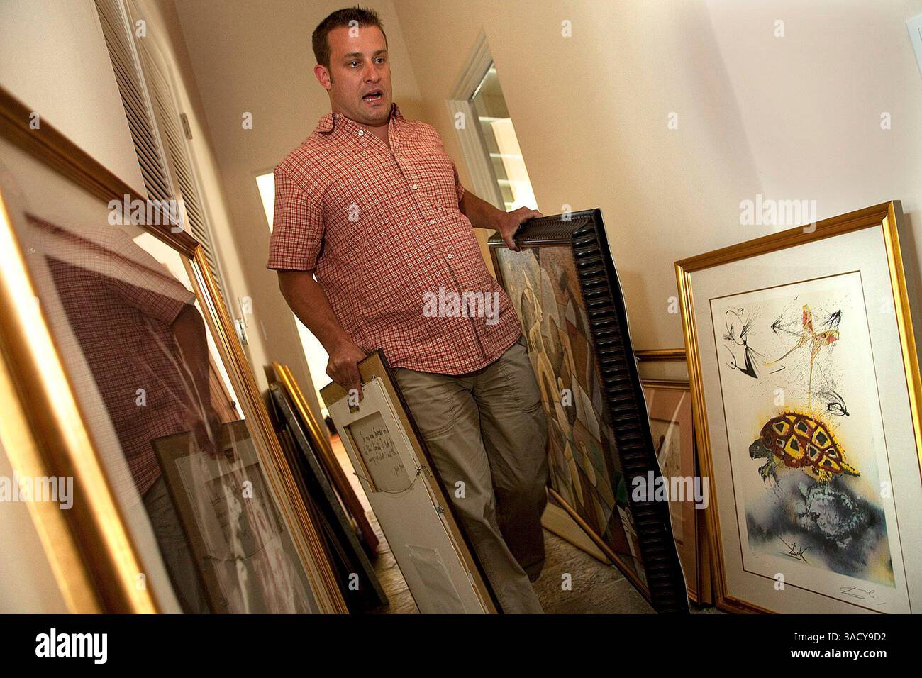 Angelo Benjamin Amadio trägt am Mittwoch, den 30. September 2009, ein Paar Gemälde durch einen Flur in seinem Haus in Pebble Beach, Kalifornien. 13 Kunstwerke im Wert von 7 Millionen wurden dem Anwesen bei einem Einbruch am Freitag entnommen. Ganz rechts ist ein Schildkrötenbild von Salvador Dali. Foto von David Royal für The Monterey County Herald (Kreditbild: Monterey Herald/ZUMAPRESS.com) Stockfoto