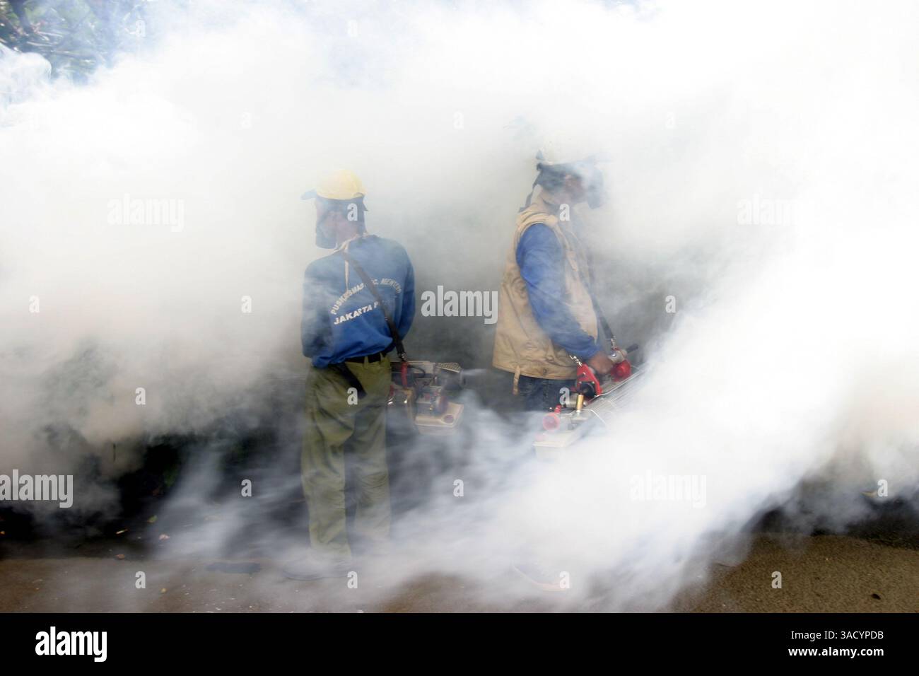 Geschützt durch Gasmasken sprühen zwei Männer Nebel im Menteng-Gebiet in Zentral-Jakarta, um die Vektormücken von Dengue zu bekämpfen, von denen die vorwiegend urbane Art Aedes aegypti ist. (Kreditbild: JiwaFoto/ZUMAPRESS.com) Stockfoto