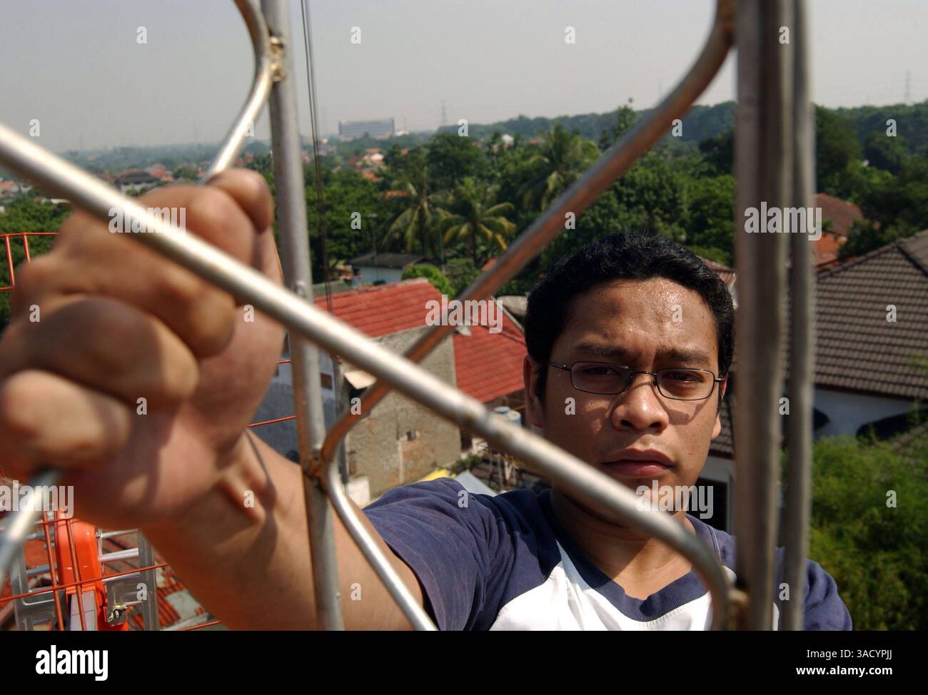 Juni 2004; Jakarta, Indonesien; Bona Simanjuntak, der Leiter des HIFI-Projekts für Poor klettert einen Mast (Antenne) auf dem Dach der Jayawisata Tourism High School. Er entwickelt drahtlose Technologie, die es Stadtbewohnern ermöglicht, Laptop-Computer oder persönlichen digitalen Assistenten mit dem Internet zu verbinden und im Internet mit Breitbandgeschwindigkeiten zu surfen, die schneller sind als drahtlose Geräte der dritten Generation. (Kreditbild: JiwaFoto/ZUMAPRESS.com) Stockfoto