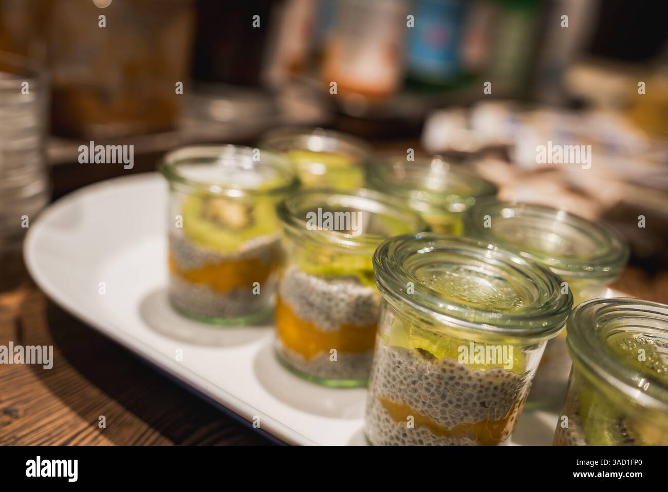 Nahaufnahme von mehrschichtigen Desserts in Glasgläsern auf einem weißen Teller Stockfoto