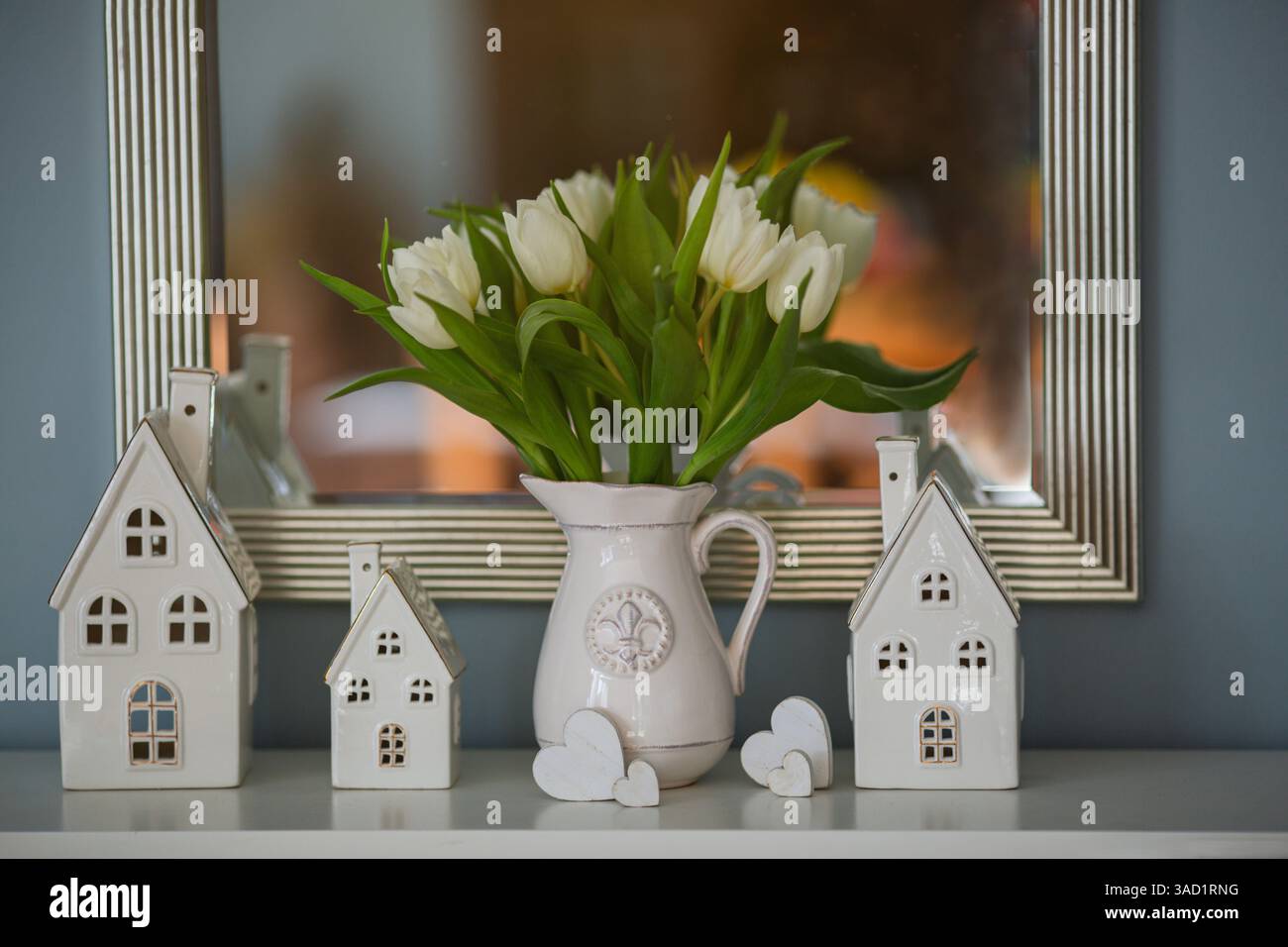 Eine Vase mit Tulpen und dekorativen Artikeln auf einer Kommode im Wohnzimmer Stockfoto