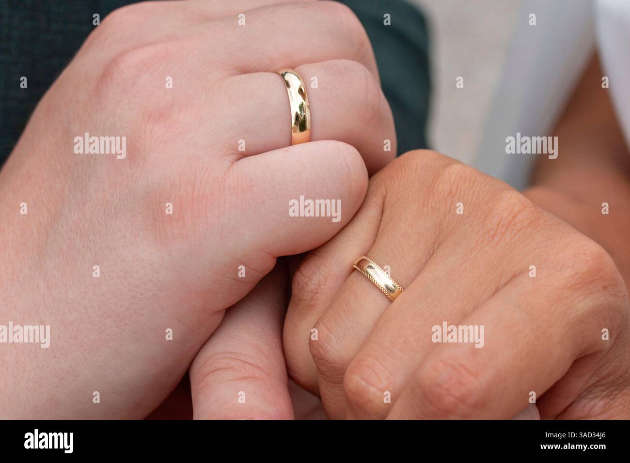 Braut und Bräutigam halten Hände, zeigen ihre Eheringe Stockfoto