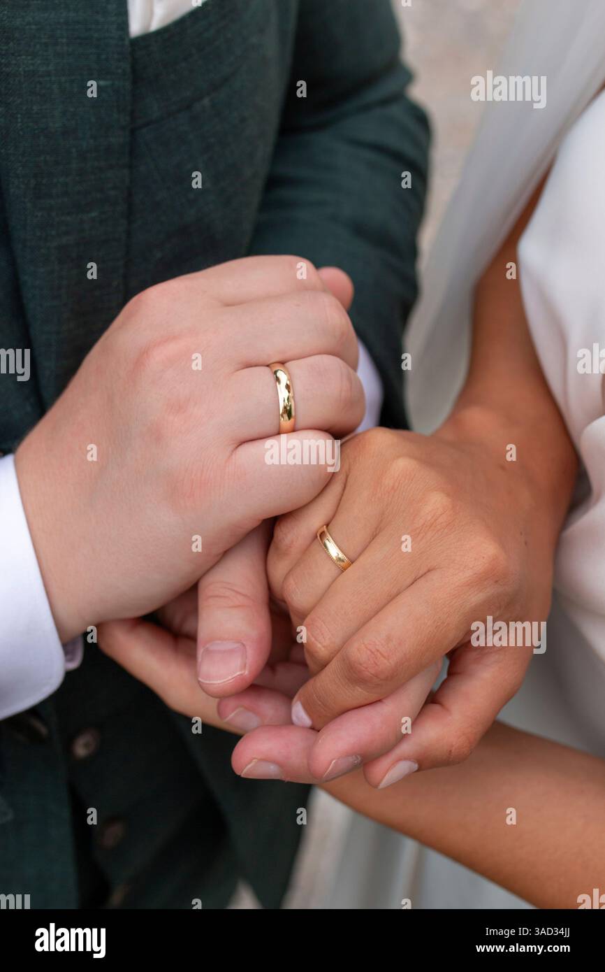 Braut und Bräutigam halten Hände, zeigen ihre Eheringe Stockfoto