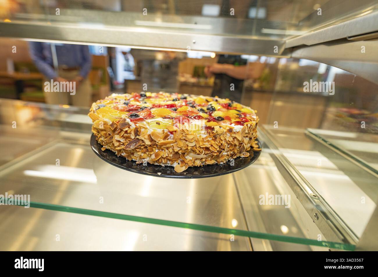 Ein kunstvoll dekorierter Kuchen mit Mandelsplittern und Obst in einer ...