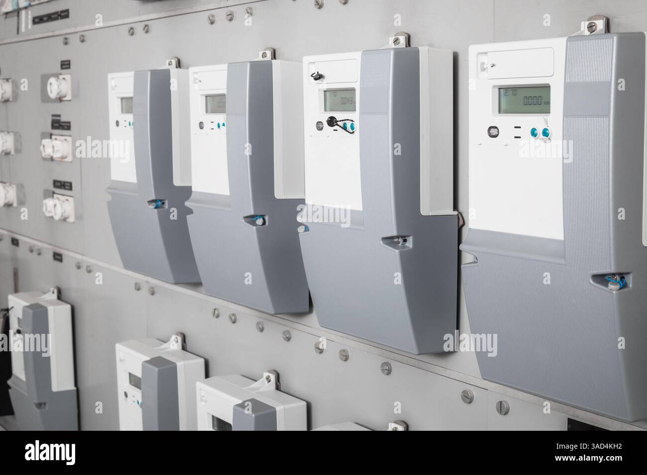 Viele intelligente Zähler im Elektroraum des Gebäudes mit defokussierten Keramiksicherungen. Digitales Messgerät überträgt den Energieverbrauch. Stromverbrauch. Stockfoto