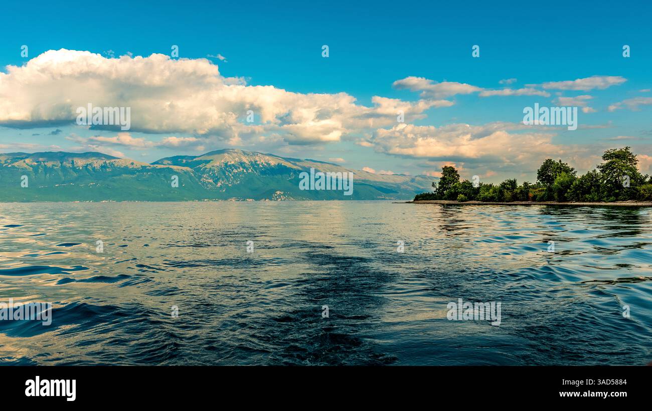 Die albanische Küste trifft auf mazedonische Gipfel am ruhigen Lake Ohrid, einem Juwel auf dem Balkan, das den azurblauen Himmel widerspiegelt. Stockfoto
