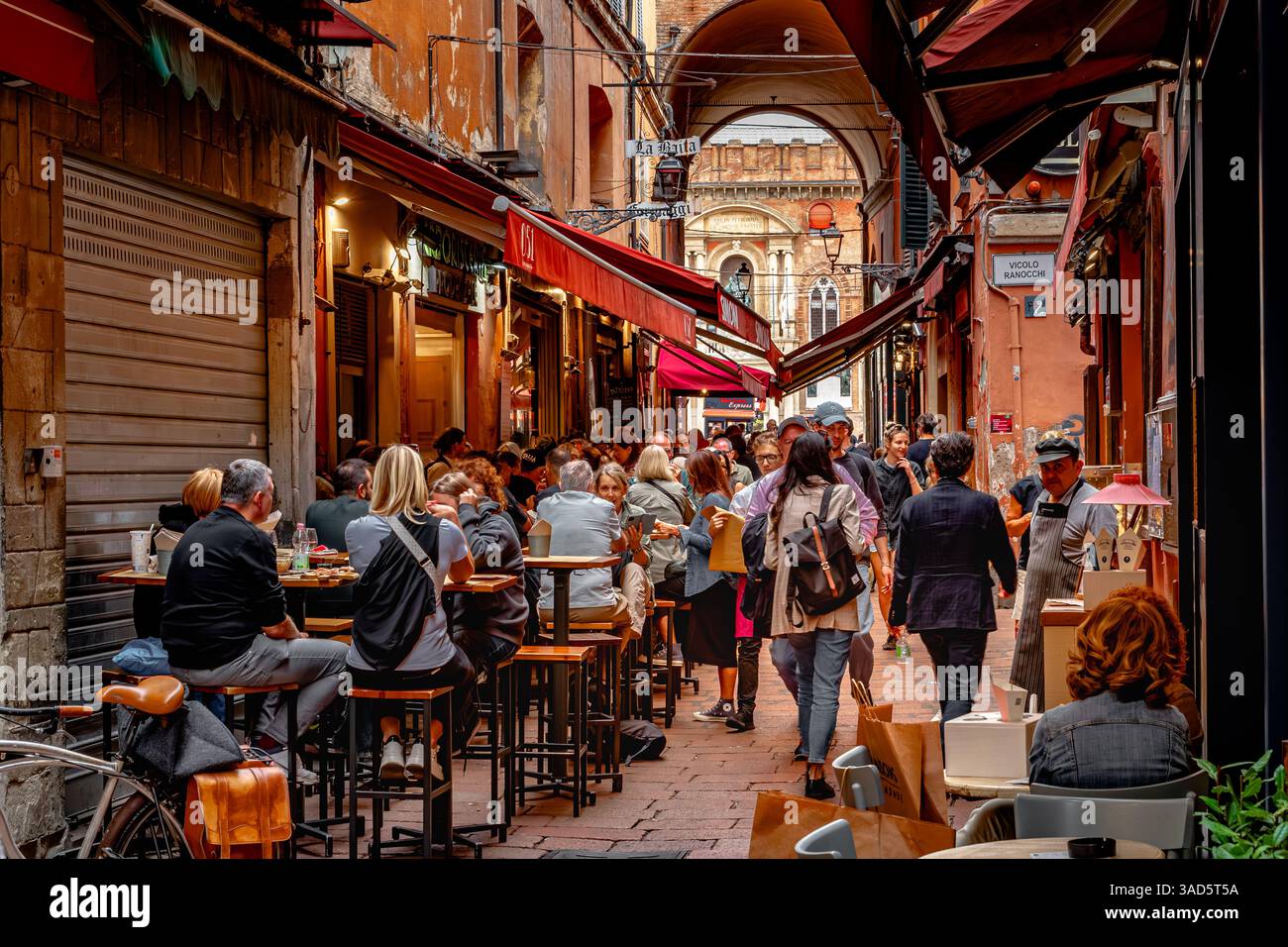 Die Leute essen draußen in einem Restaurant entlang der Via Pescherie Vecchie, einer engen Straße voller Restaurants und Restaurants in Bologna, Italien Stockfoto