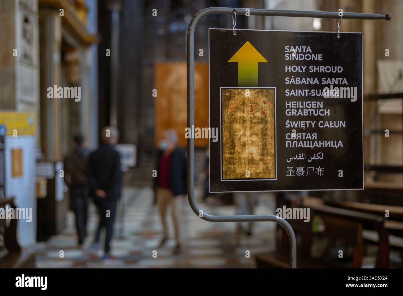 Ein mehrsprachiges Schild in Turin, Italien, mit einem Pfeil in Richtung Santa Sindone oder Heiliges Grabtuch, das Touristen und Pilger anzieht. Stockfoto