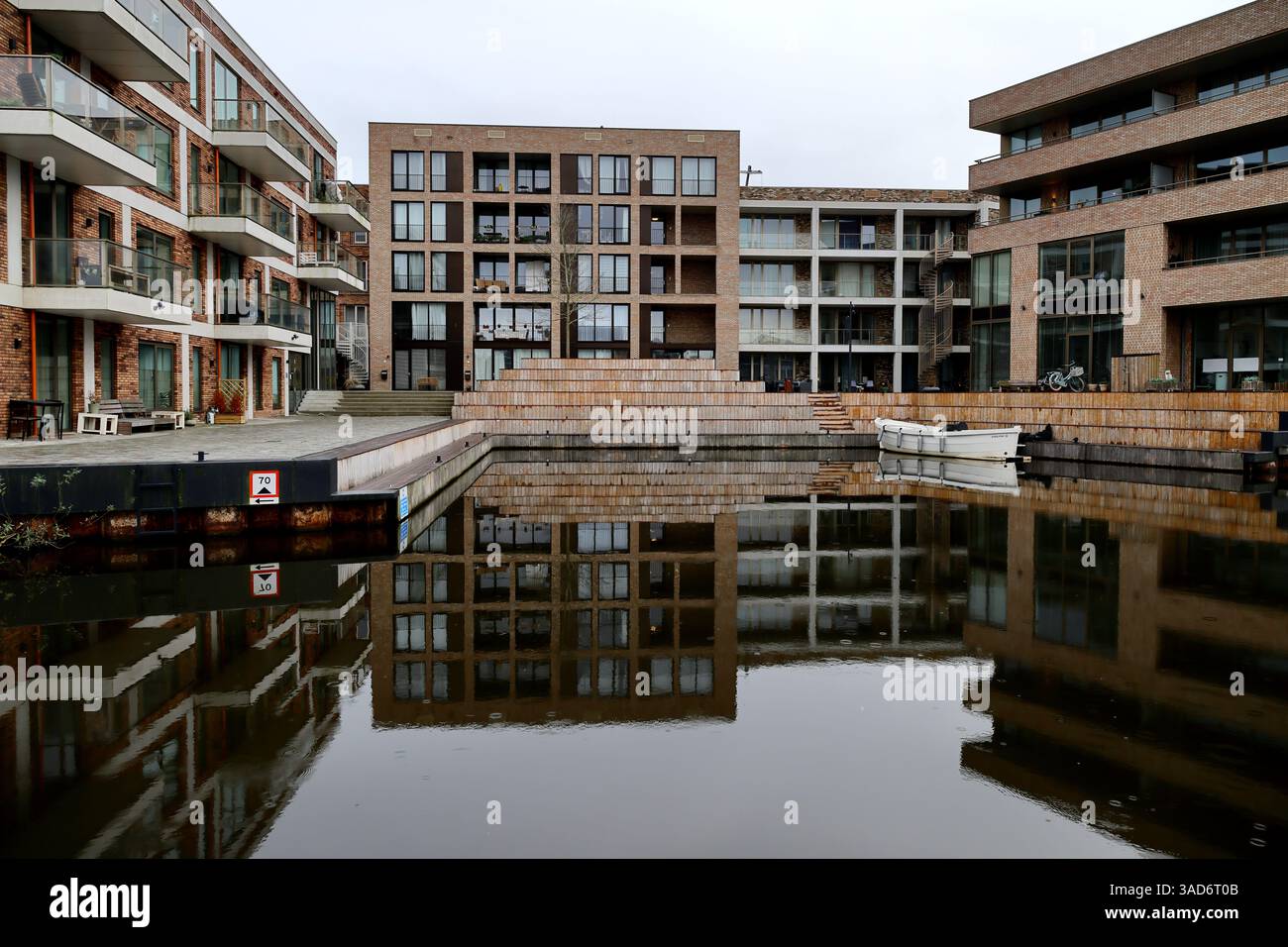 Moderne Apartments aus Ziegelstein und Glas im Punt Sniep in Diemen umschließen den Kanal, mit einem angedockten Boot und einem sauberen Design, das die urbane Ruhe widerspiegelt Stockfoto