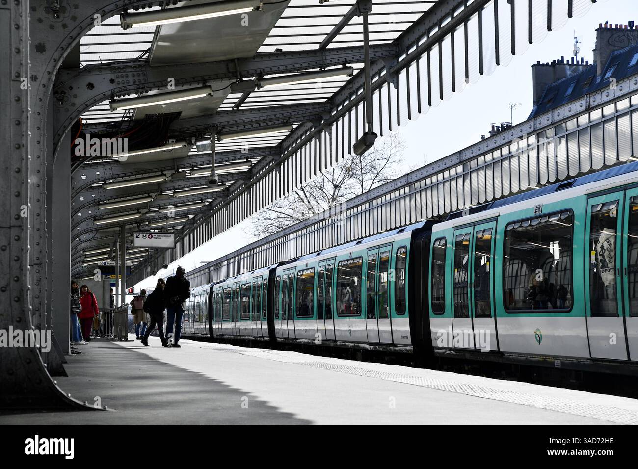 eine erhöhte Außenplattform einer Pariser Métrostation mit einem grün-weißen MF-67-Zug, der daneben hält Stockfoto