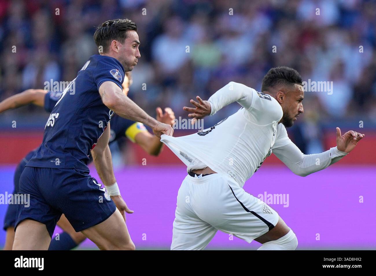 PSG's Fabian Ruiz, left, challenges for the ball with Angers' Jim Allevinah during the French League One soccer match between Paris Saint-Germain and Angers at Parc des Princes stadium in Paris, Saturday, April 5, 2025. (AP Photo/Michel Euler) Stockfoto