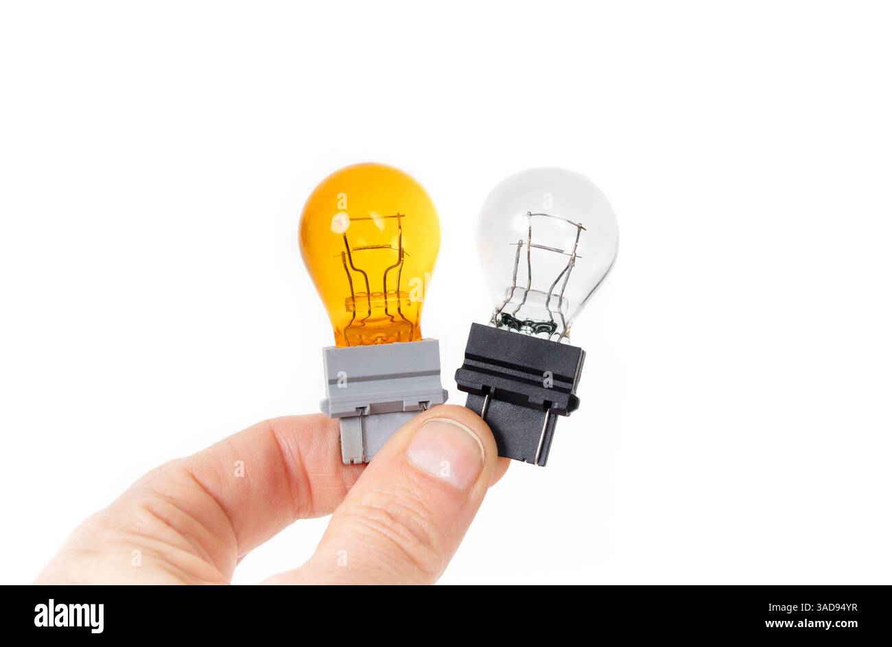 Blinkleuchten für Fahrzeugscheinwerfer. Frauenhand hält gelbe und klare Miniaturlampe. Gelbes Licht ausgebrannt. Glühlampe für Blinker oder Anzeige Stockfoto