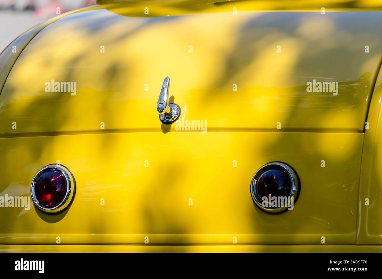 Nahaufnahme des Kofferdeckels eines gelben Roadsters und der Taillenseiten unter einem schattigen Baum Stockfoto