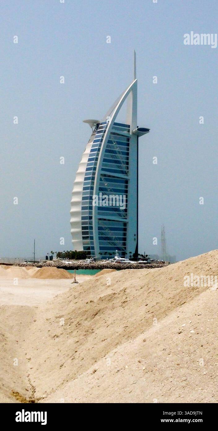 Ein Blick auf das berühmte Burj Al Arab Hotel in Dubai mit seiner einzigartigen segelähnlichen Architektur vor klarem Himmel. Im Vordergrund befindet sich eine sandige Terre Stockfoto