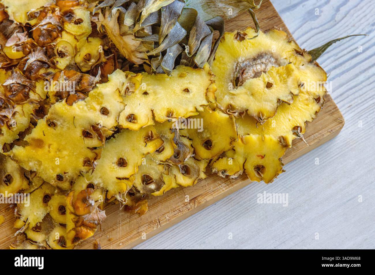 Nahaufnahme einer frisch geschälten und geschnittenen Ananas auf einem hölzernen Schneidebrett. Lebendiges und detailreiches Foto von tropischer Frische, perfekt für culina Stockfoto