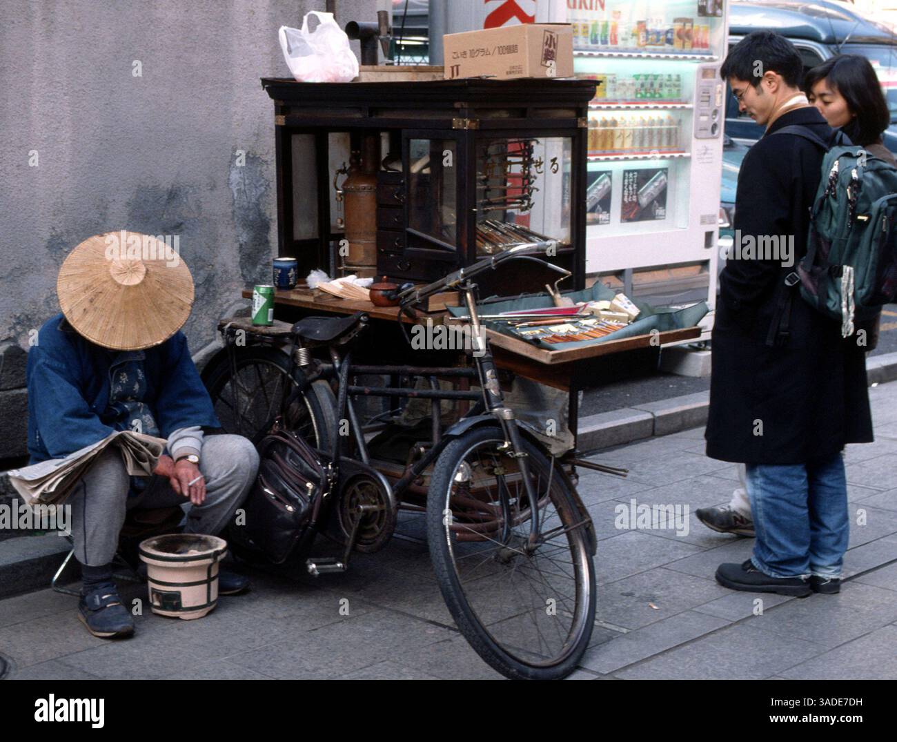 April 2000; Tokio, Japan; Ein junges Paar prüft japanische Rohre, die von einem Straßenverkäufer im Stadtteil Asakusa in Tokio verkauft werden. (Bild: Barry Cronin/ZUMAPRESS.com) Stockfoto