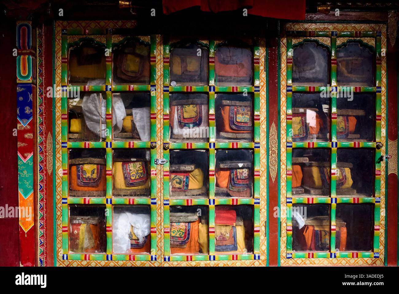Kunstvoller Holzschrank mit tibetisch-buddhistischen Schriften, aufbewahrt in gestickten Stoffhüllen, Shey Palace Kloster, Leh, Ladakh. Stockfoto
