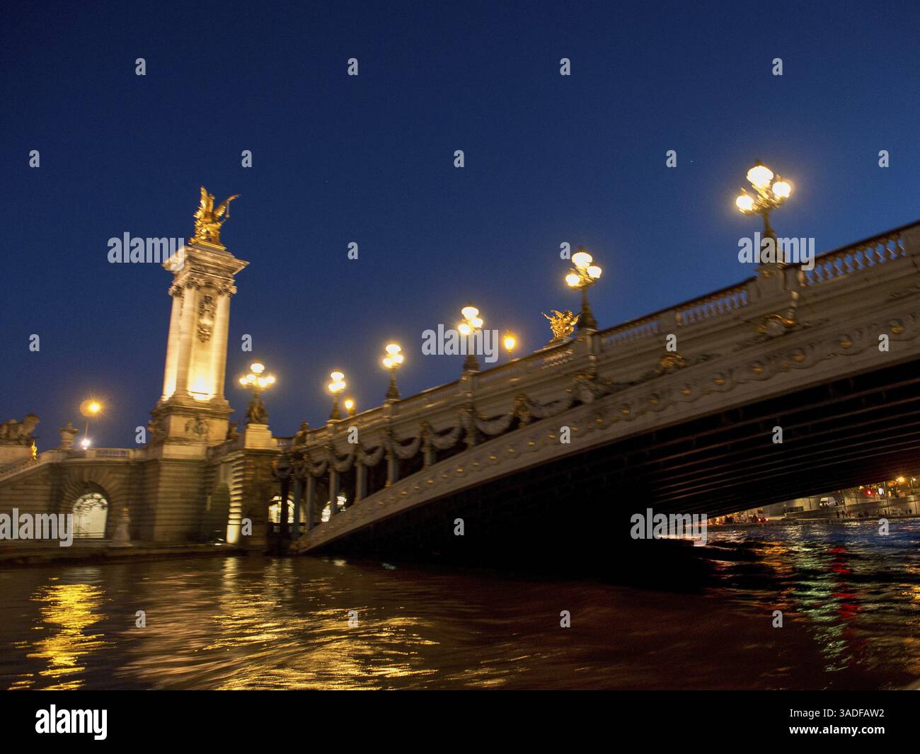 Blick auf die Pont Alexandre III bei Nacht mit beleuchteten Straßenlaternen und Wasserreflexion, Paris, Frankreich, Europa Stockfoto