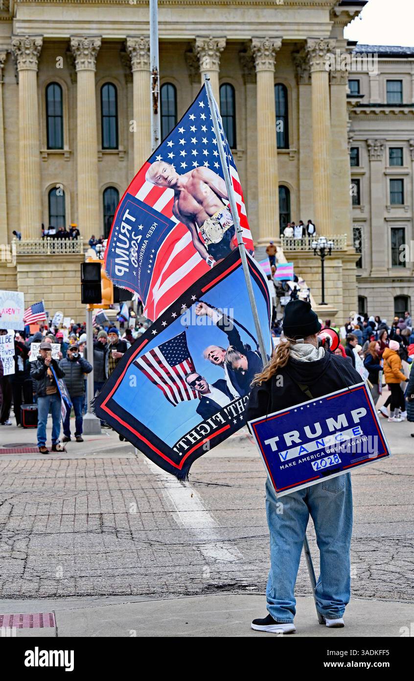 TOPEKA KANSAS, USA - 5. APRIL 2025 der einsame Donald Trump-Unterstützer weht Flaggen von der anderen Straßenseite der Hauptrallye Stockfoto
