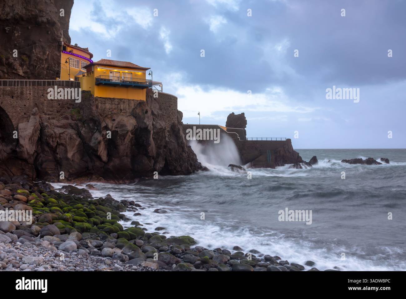 Gebäude über dem steinigen Strand in Ponta do Sol, Insel Madeira, Portugal, am Abend Stockfoto