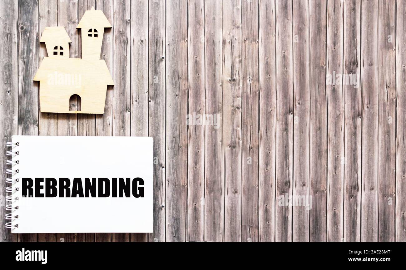 Das Rebranding-Wort ist auf einem Notizbuch und einem hölzernen Hintergrund geschrieben Stockfoto