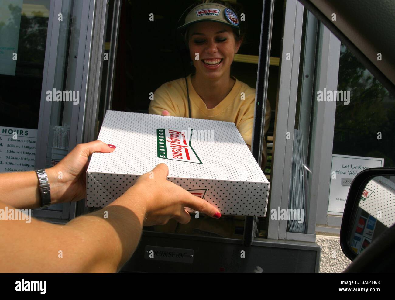 Oktober 2003; Laguna Niguel, CA, USA; Krispy Cream Donuts erobern die Welt im Sturm und die Leute scheinen nicht genug davon zu bekommen. Ein Kunde, der ein Dutzend glasierte Donuts vom Drive-Thru-Mitarbeiter kauft. Sie haben mittlerweile über 300 Filialen weltweit. (Bild: Ruaridh Stewart/ZUMAPRESS.com) Stockfoto