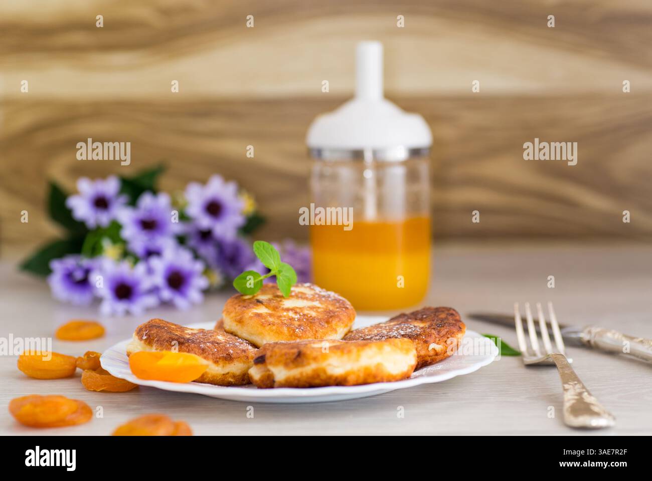Ruddy-Käsepfannkuchen mit Honig und Minze auf einer weißen Platte. Stockfoto