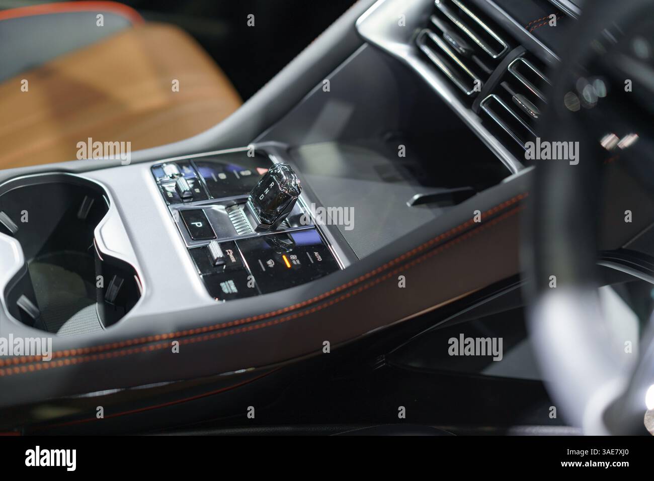 Nahaufnahme eines modernen Schaltschalters in einer hochglänzenden Fahrzeugkonsole, der Komfort, Stil und Innenausstattung unterstreicht. Stockfoto