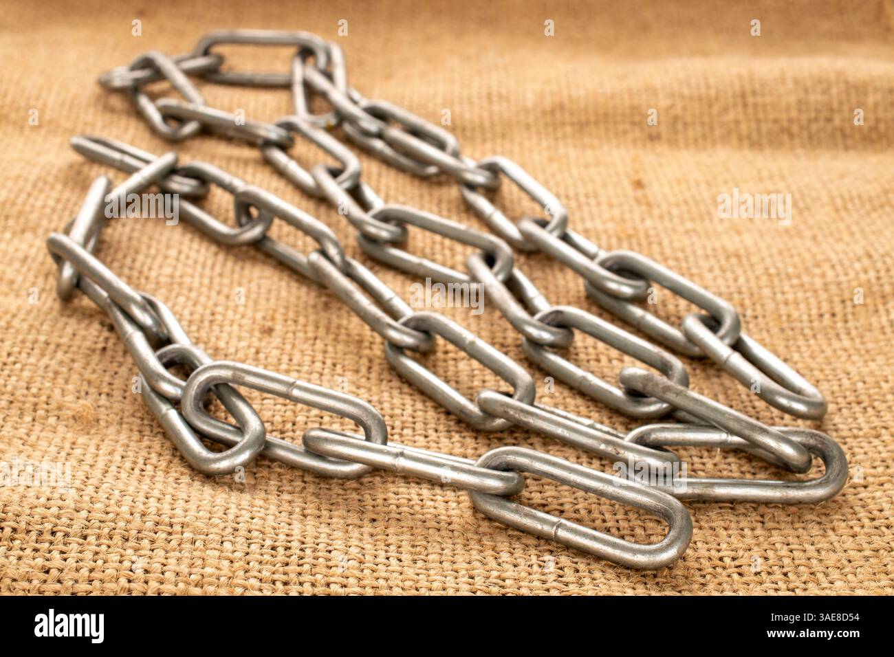 Ein Stück Metallkette auf Jute-Tuch, Makro. Stockfoto