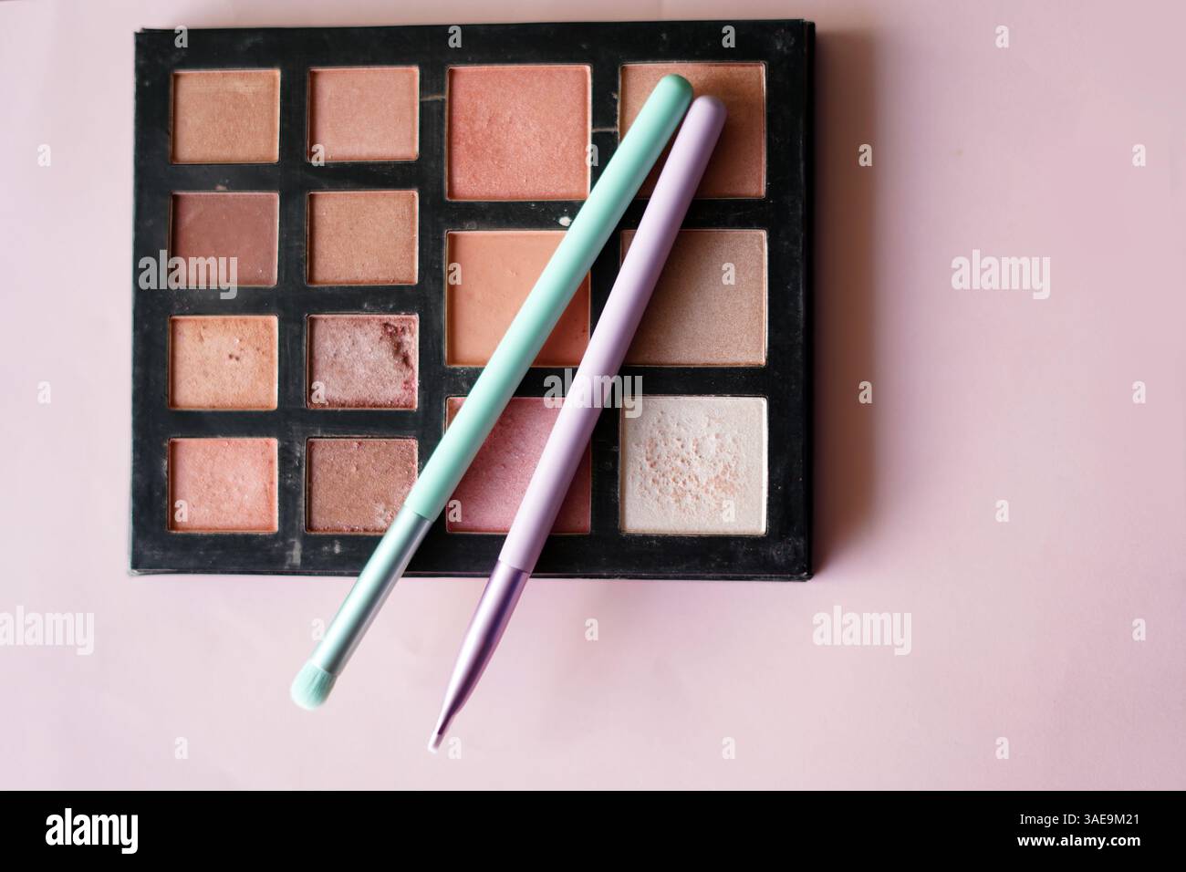 Make-up-Palette mit Pinseln auf hellrosa Hintergrund Stockfoto