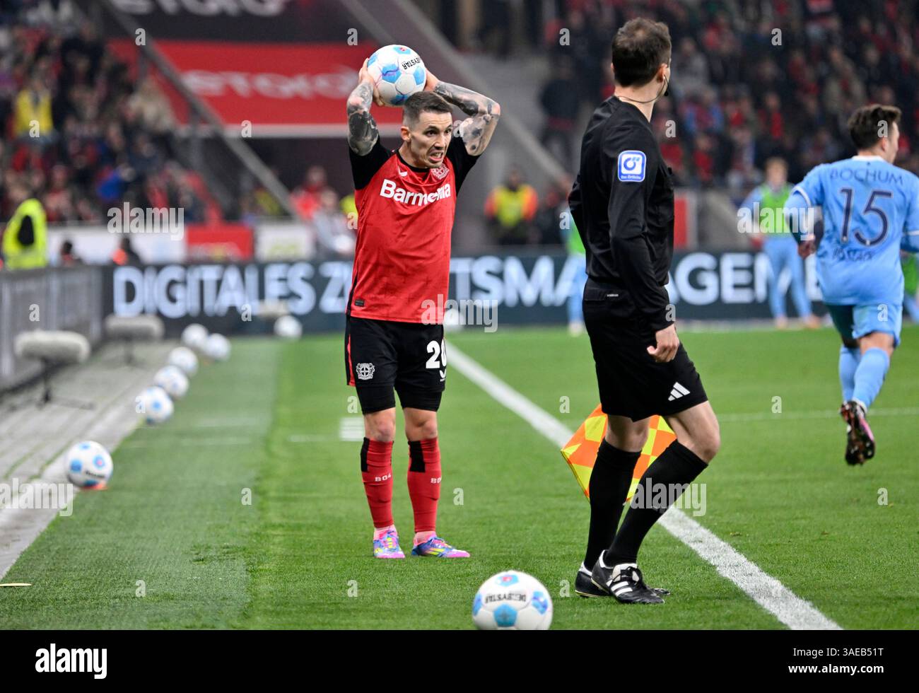 BayArena Leverkusen Deutschland 28.3,2025, Fußball: Bundesliga-Saison 2024/2025 Spieltag 27 , Bayer 04 Leverkusen (B04, rot) vs. VfL Bochum (BOC, blau) — Alejandro Grimaldo (B04) hat einen der zusätzlichen Bälle aufgenommen, die seitlich auf dem Spielfeld platziert werden, damit sie von Spielern schnell aufgenommen werden können, nachdem ein Spielball aus dem Spielfeld geworfen wurde und einen Wurf-in ausgeführt wird. Abbildung 3 einer Serie von 3 Stockfoto