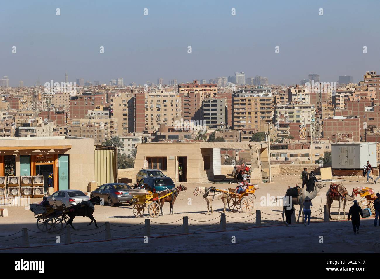 Pferdekutschen und Wagen parken im Pyramidenkomplex mit Blick auf die Stadtentwicklung von Kairo Stockfoto