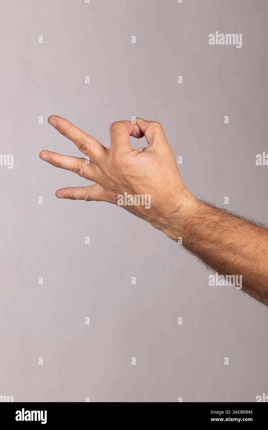 Haarige männliche Hand, die eine Geste mit drei gestreuten Fingern und zwei Fingern zeigt, die Zartheit und einen großartigen Geschmack des Essens ausdrücken Stockfoto