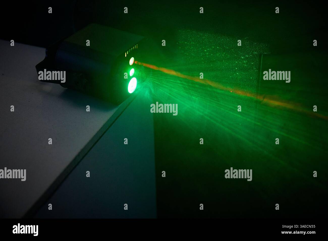 Leuchtend vor Rätsel, intensive grüne und bernsteinfarbene Laser durchdringen die Dunkelheit und erinnern an futuristische Technik, Sicherheitssysteme oder dramatische Stimmungsbeleuchtung. Stockfoto