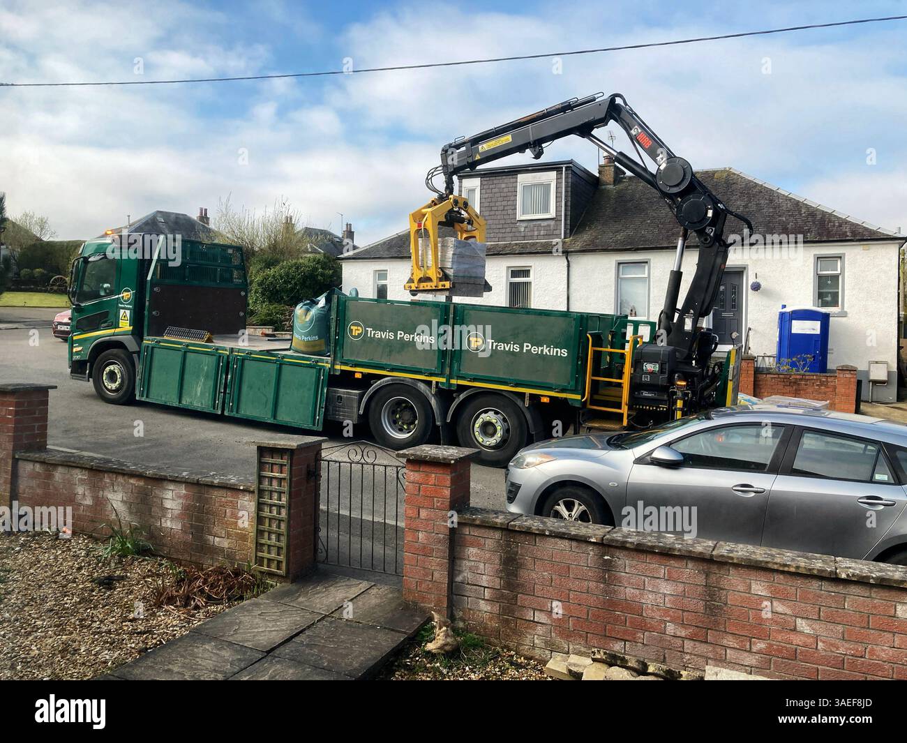 Travis Perkins Flachlader mit Bauarbeiten Lieferung einer Palette von Ziegeln - Smartphone-aufgenommenes Stockfoto
