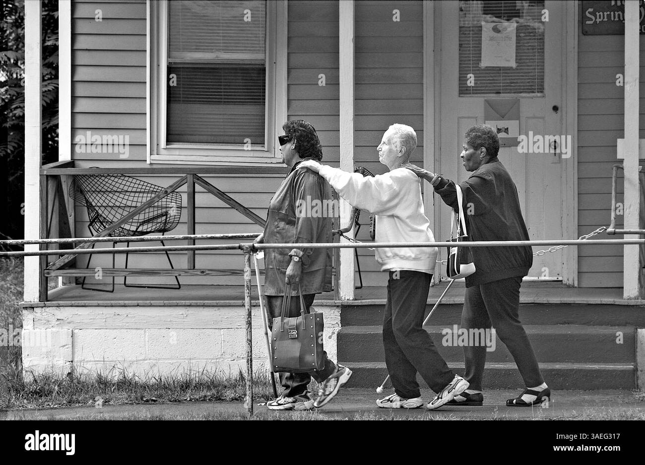 Juli 2004; Spring Valley, NY, USA; KALOUTIE SANKAR ist stark sehbehindert, kann aber Licht und Schatten unterscheiden. Er führt MARY SANDER an und MARGARET WILTSHIRE ist blind. Versteckt in den Hügeln des Spring Valley, New York, befindet sich ein Sommerschlaflager für Blinde. Die 35 Hektar großen Grünflächen sind normalerweise voll mit Kindern, aber zwei Wochen im Hochsommer werfen blinde Erwachsene die blinden Kinder raus und übernehmen das Camp für sich. YouÕd weiß es aber kaum, denn die erwachsenen Camper, viele in den 70ern und 80ern, verhalten sich wie Kinder. Sie werfen ihre weißen Stöcke weg, nehmen ihren Führer Stockfoto