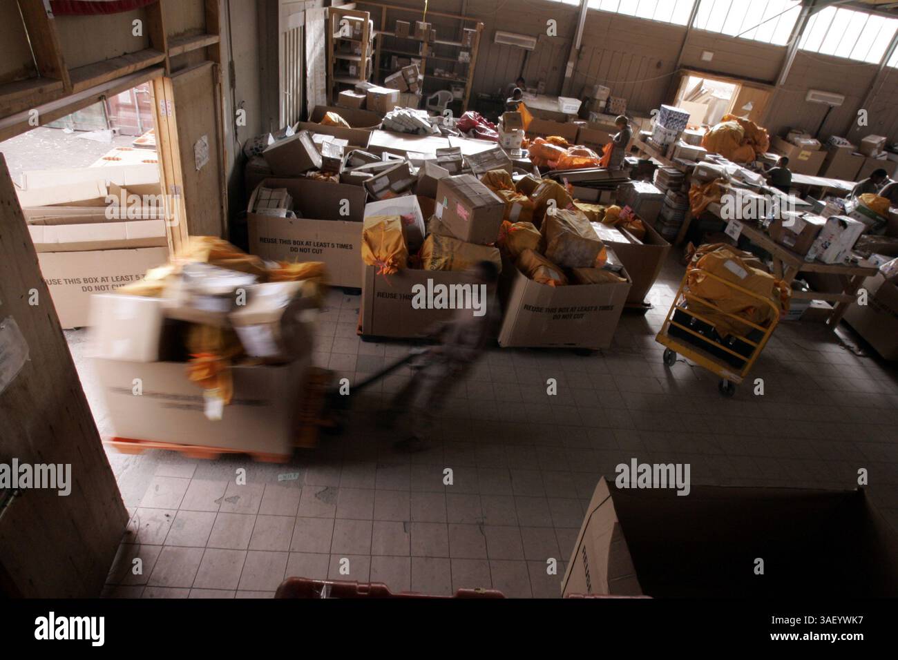 27. November 2004; Camp Taqaddum, Irak; Lance CPL. DARYL E. WRIGHT, ein Informationstechniker der 1st Force Service Support Group, zieht am 27. November 2004 in Camp Taqaddum, Irak, einen Wagen voller Pakete in das Postamt, um sie zu sortieren. Wright, ein 22-jähriger Ellenwood, Ga., gebürtig, meldete sich freiwillig an, um die Urlaubspost bei der Post zu sortieren. Die 1. FSSG ist für die Lieferung aller Vorräte wie Lebensmittel, Wasser, Munition, Treibstoff, medizinische Vorräte und Post an alle anderen Marinestreitkräfte im Irak. Die Post wird auf Militärkonvois von Camp Taqaddum an die Marine-Truppen geliefert, die durch operieren Stockfoto