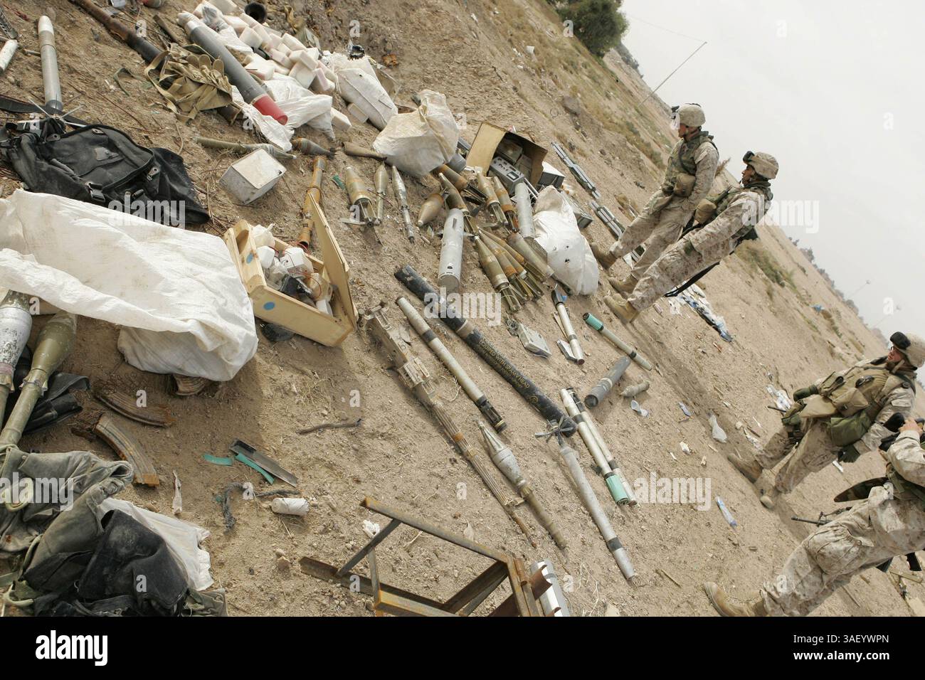 14. Dezember 2004; Falludscha, Irak; Marines mit Kompanie C, Combat Service Support Battalion 1, sehen Sie sich die Munitionsdeponie an, die sie im Südwesten von Falludscha entdeckten, als sie Schutt von den Straßen der Stadt am 14. Dezember 2004 räumten. Die Kompanie, Teil des Combat Service Support Bataillons 1, bereitet die Stadt auf die Rückkehr ihrer Bewohner vor. CSSB-1 unterstützte Infanterieeinheiten durch die Wartung, den Bau und die Befestigung der Ausrüstung, die Lieferung von Versorgungsgütern, den Abriss von Hindernissen und die Suche nach Waffenlagern und Minen. Die Operationen verlagern sich, um die Bedürfnisse der zurückkehrenden Fallujaner zu erfüllen, Charlie com Stockfoto