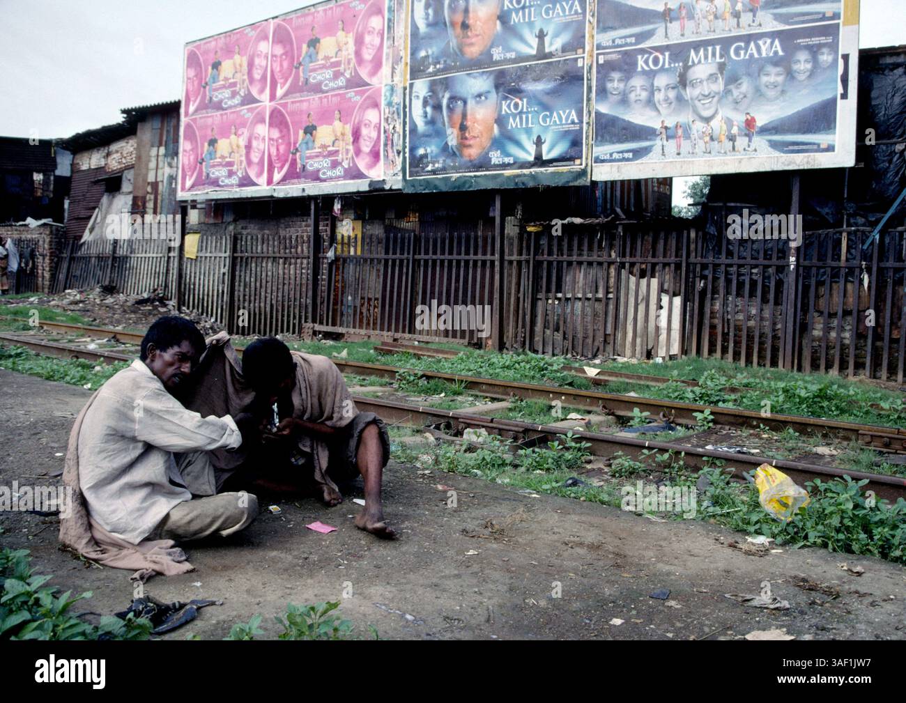 20. April 2003; Bombai, INDIEN; Drogenkonsumenten missbrauchen Heroin unter den wachsamen Augen von Bollywoods neuesten Stars neben Eisenbahngleisen in Bombay, Indien. Stockfoto