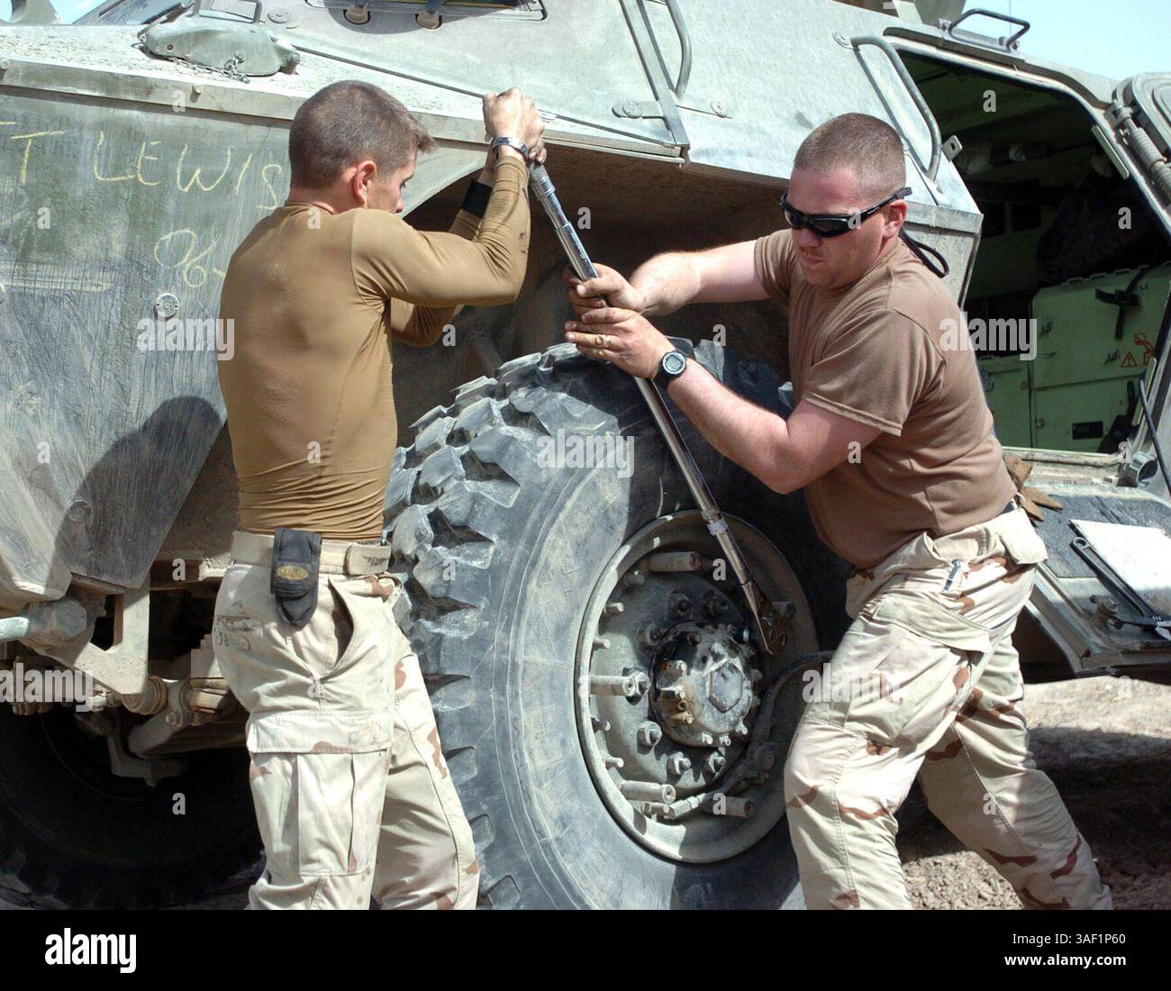 April 2005; Camp Liberty, Irak; Sgt. Mark J. Meunier, (links) Militärpolizist, 940. MP-Kompanie, 503. MP-Bataillon, Fort Bragg, N.C. und Sgt. Anthony Faul, MP, 940., ziehen die Radmuttern ihres gepanzerten Sicherheitsfahrzeugs M1117 in Camp Liberty fest. Stockfoto