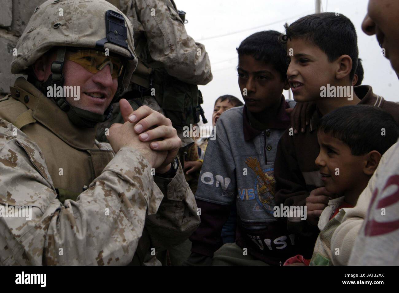 9. März 2005; Falludscha, Irak; Marinestützpunkt MATTHEW S. WEEMS, 33-jähriger Kaplan für das 3. Bataillon, 4. Marines, Regimentskampfteam 1, spricht mit irakischen Kindern während einer Patrouille durch die Stadt Falludschah, Irak, am 9. März. Weems und sein Spezialist für religiöse Programme, Petty Officer 2nd Class Aaron G. Neely, nehmen an vielen verschiedenen Aspekten der Operationen des Bataillons Teil, um eine Präsenz unter den Marines zu erhalten. Stockfoto
