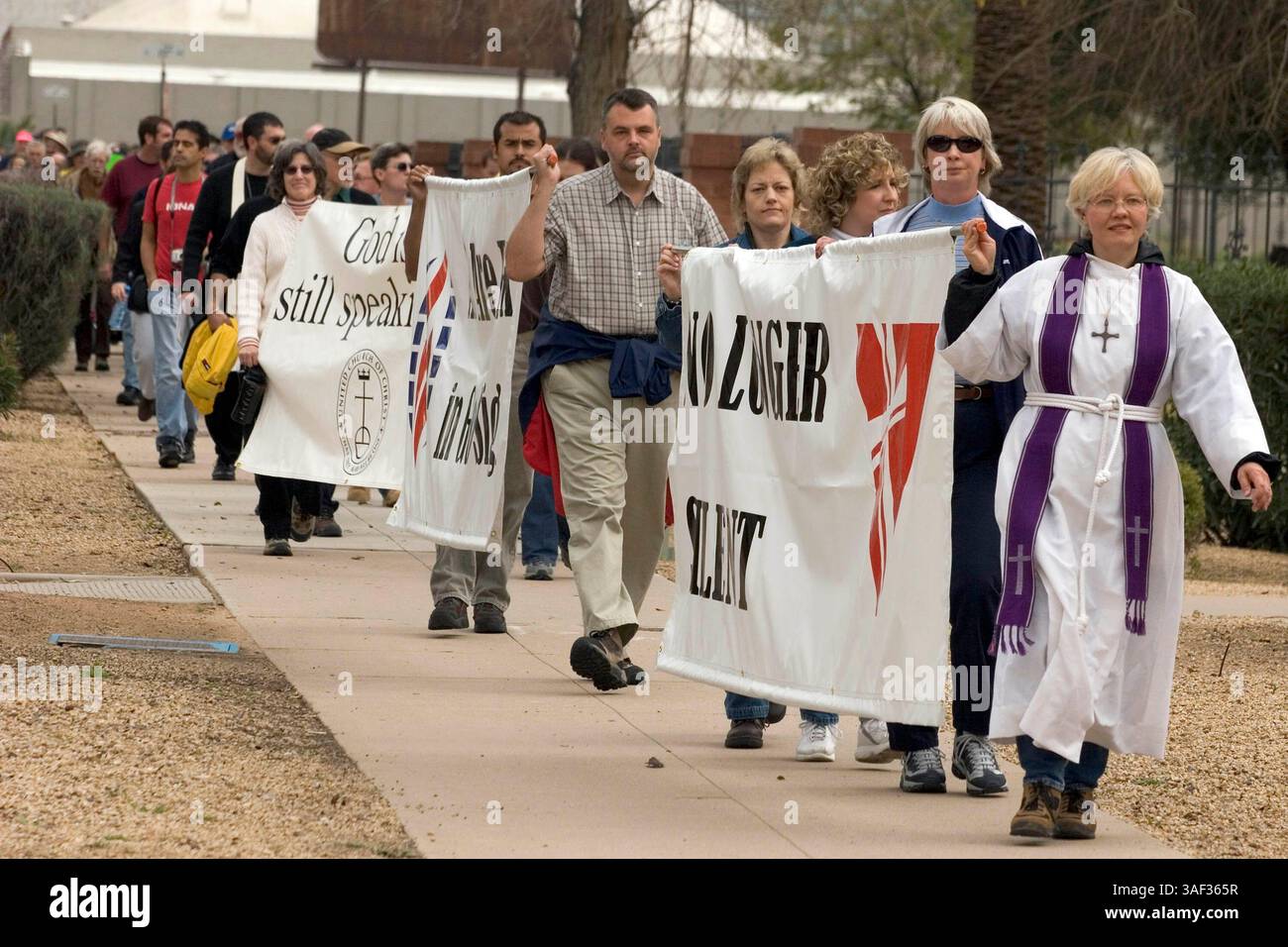 Januar 2005; Phoenix, AZ, USA; Rev. STEPHANIE BIKEL (R) von Desert Surprise United Church of Christ in Surprise, AZ, führt einen stillen marsch von Geistlichen durch die Innenstadt von Phoenix in die Hauptstadt des Bundesstaates Arizona, um gegen die Pläne der Legistlatures zu protestieren, eine Verfassungsänderung des Staates zu debattieren, die schwule Ehe verbieten würde. Der Klerus, Mitglieder von nicht mehr Silent, einer Organisation christlicher Geistlicher, die die Rechte schwuler Ehe unterstützt. Etwa 200 Menschen nahmen an dem marsch Teil. Stockfoto