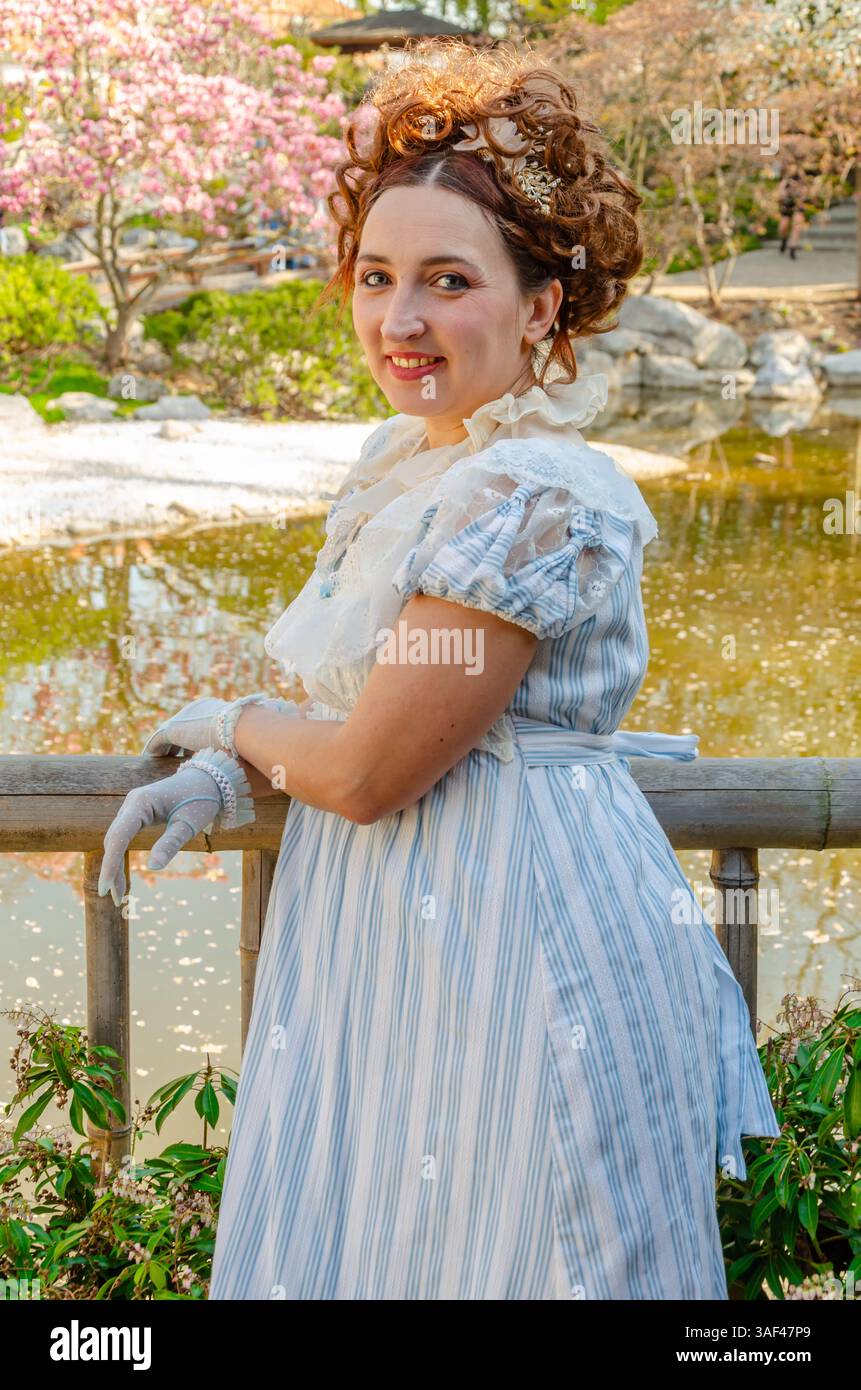 Eine Dame in einem Vintage-Kleid mit Handschuhen repräsentiert die Mode der Regency-Ära vor dem Hintergrund der Natur Stockfoto