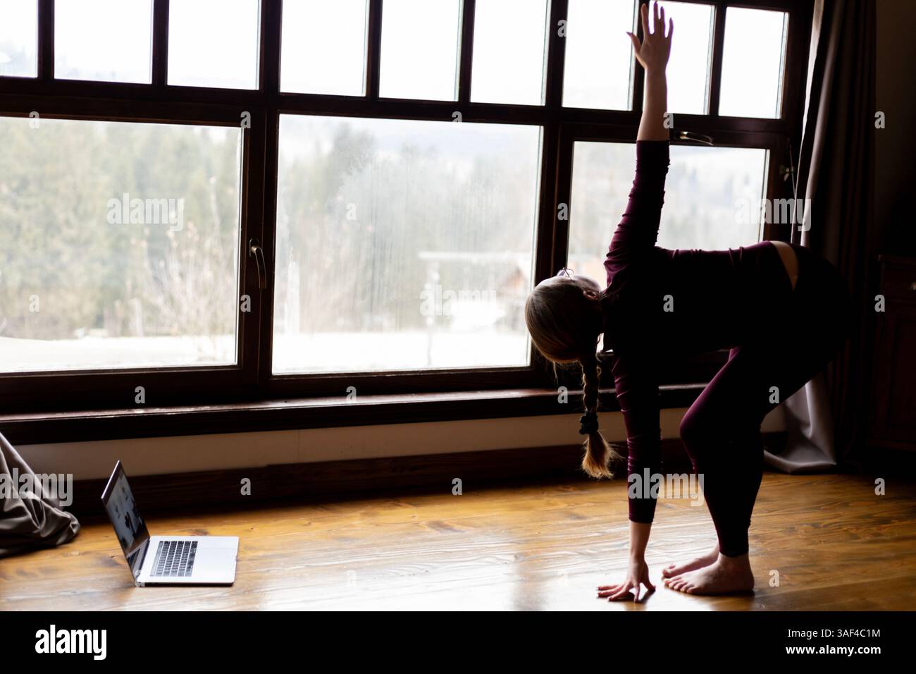Frau macht Yoga-Übungen zu Hause, sieht sie auf einem Video auf ihrem Laptop Stockfoto