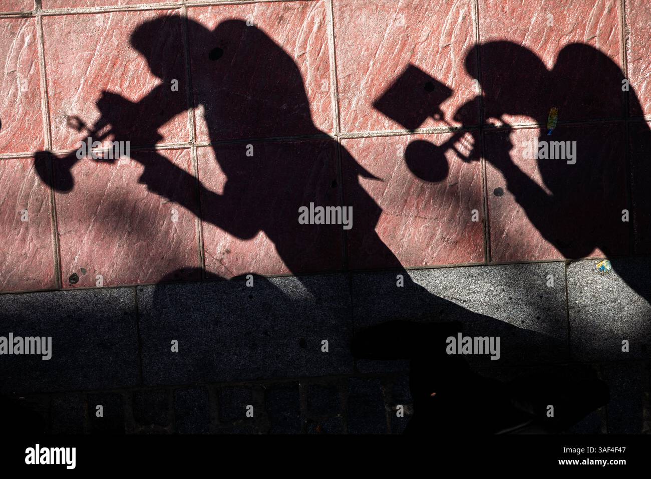 Künstlerische Schatten von Blasmusikern auf einer Straße in Sevilla, Spanien. Stockfoto